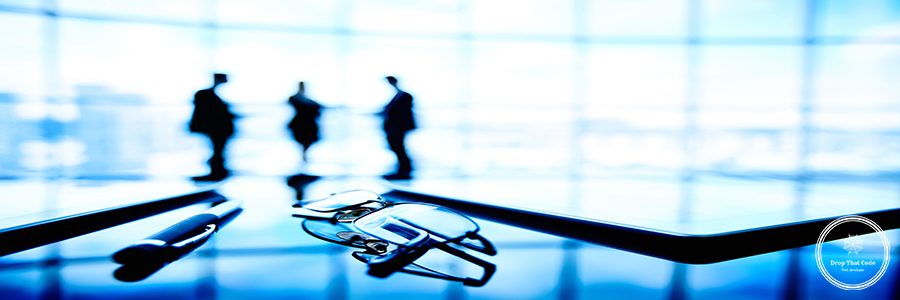 Image of eyeglasses, touchpads and pen at workplace with businesspeople on the background