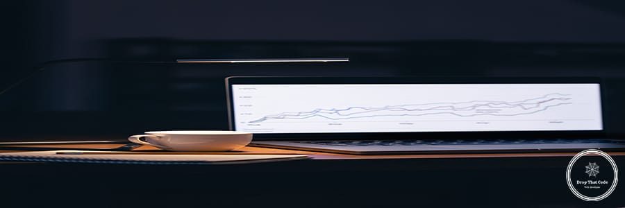 Computer in a dark room with graphs on the screen. Laptop monitor with stock chart at workplace.