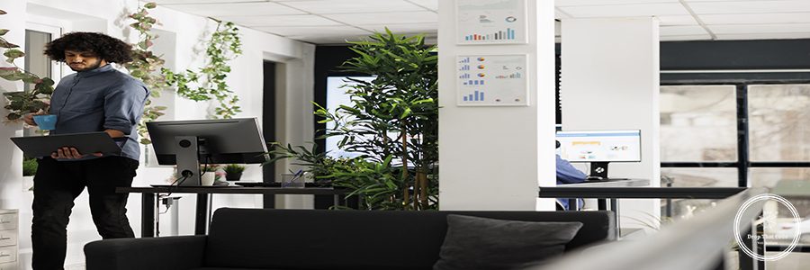 Arab employee drinking coffee, holding laptop and working at strategy while standing in business office. Young businessman checking start up company financial report on portable computer