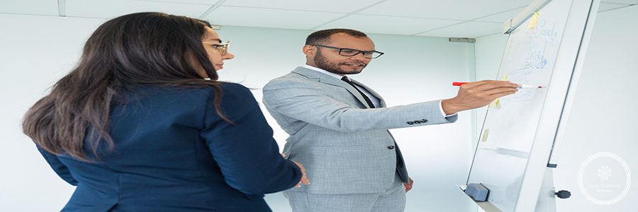 Excited male professional presenting analytics to his team. Business man drawing graphs on white board, his two female colleagues looking at drawing. Statistics concept