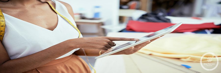 Close-up of young fashion designer pointing at touchscreen, she working on digital tablet for dress designs