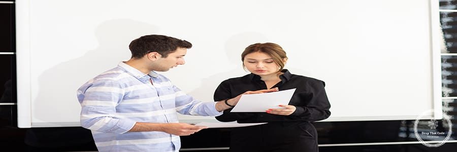 a front view young attractive businesswoman in black shirt along with young man discussing graphics on the desk while young lady presents her work reading document job building presentation