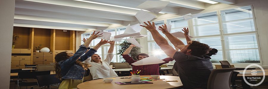 Group of excited business executives throwing paper and having fun in office