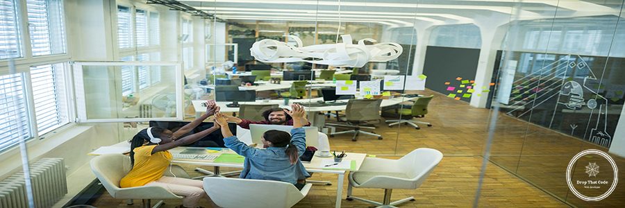 Group of graphic designers giving high five to each other in office