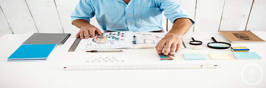 Hands of young businessman sitting at table with notepad. White modern office background.