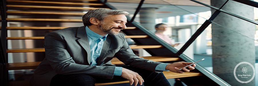 Happy mid adult businessman text messaging on cell phone while sitting on staircase.