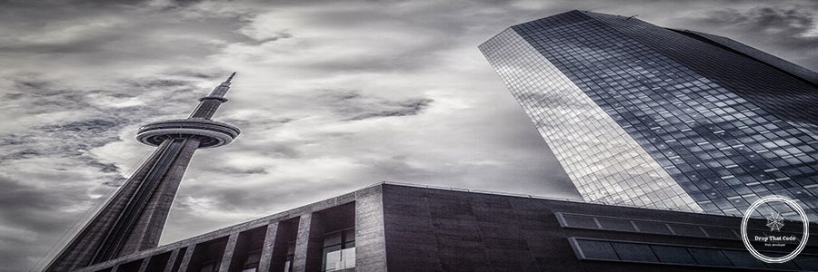 low-angle-view-cn-tower-by-skyscraper-against-cloudy-sky