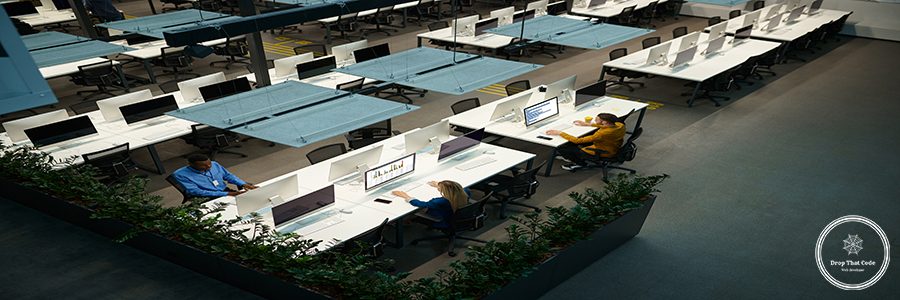 Team of managers works on computers in IT office, top view. Professional teamwork and planning, group brainstorming, modern company interior on background