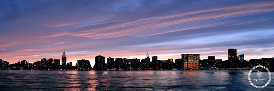 New York City Manhattan midtown silhouette panorama at sunset with skyscrapers and colorful sky over east river