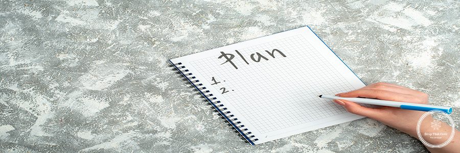 Overhead view of hand writing on spiral notebook on gray background