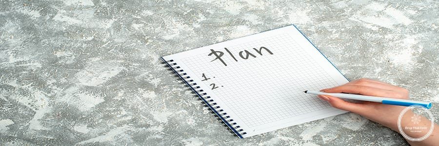 Overhead view of hand writing on spiral notebook on gray background