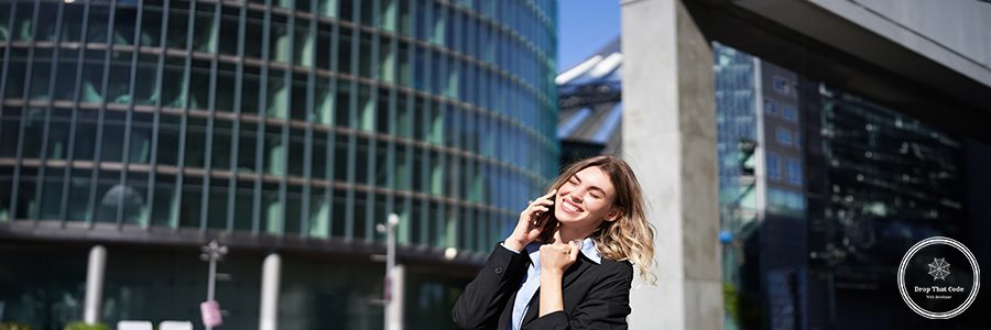 Pleased businesswoman celebrates on street, talking on mobile phone, receive good news on call. Corporate people concept