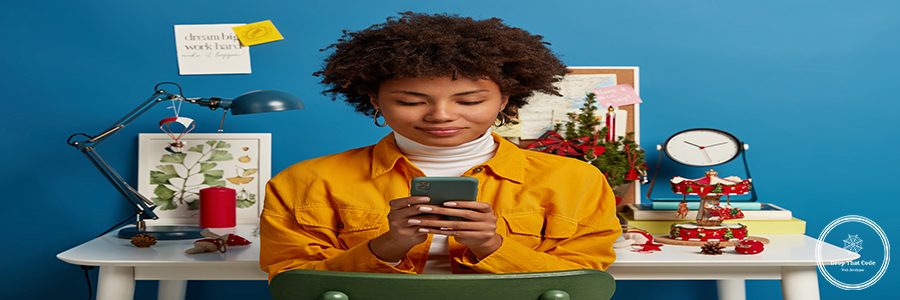 Pleased female student takes break from autodidact, uses cellular for chatting online, browses application, sends text message, checks mail via wifi, sits on chair near workplace, blue background