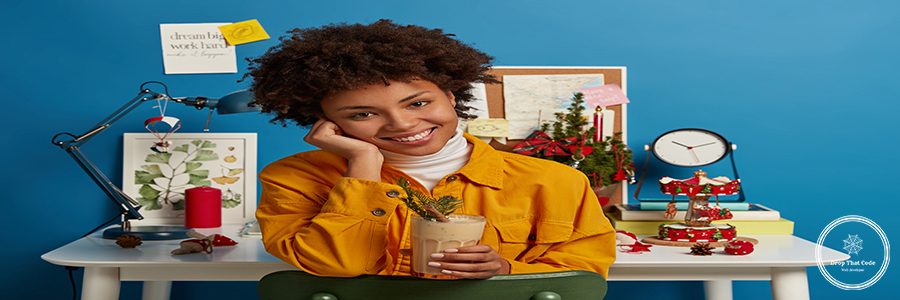 Positive dark skinned woman drinks traditional Christmas beverage, wears yellow jacket, enjoys eggnog, sits near cozy coworking space, smiles positively, poses in study room, prepares for exam