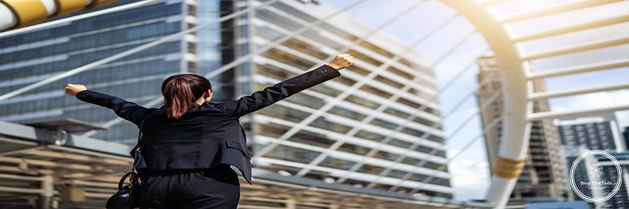 successful business woman with arms raised in the city