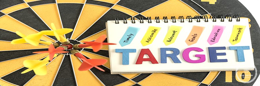 six dart in bullseye with words target on the notebook with handwriting timely achievable relevant goals education teamwork over dartboard background, Business success concept