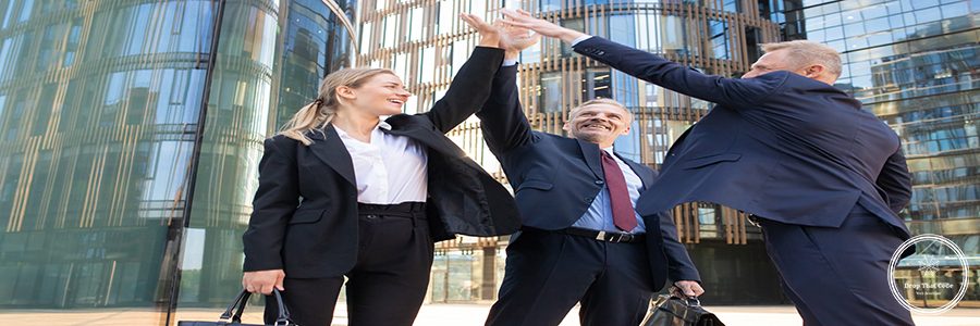 Three cheerful businesspeople giving five and smiling. Confident happy colleagues celebrating successful deal together, standing outdoors and rising hand up. Teamwork and partnership concept