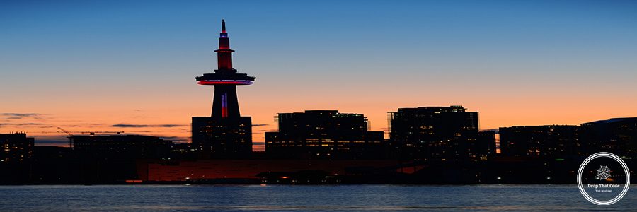 Toronto city skyline silhouette at sunset over lake with urban skyscrapers.