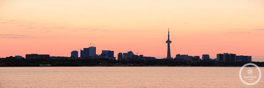 Toronto sunrise silhouette over lake with red tone.