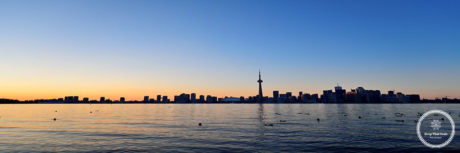 Toronto sunset silhouette at dusk over lake with urban architecture.