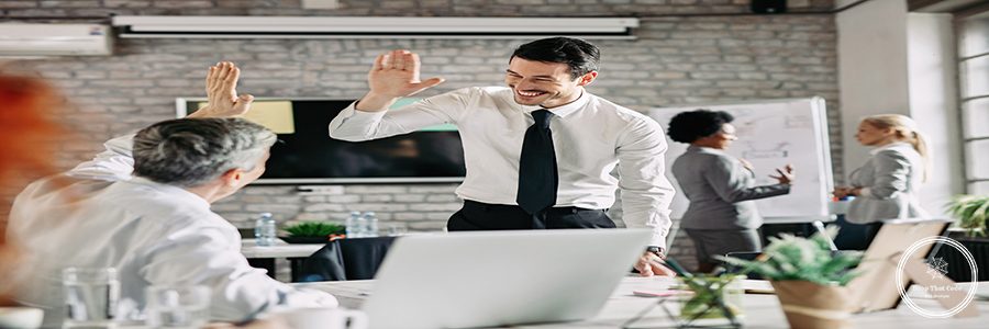 Two businessmen congratulating to each other on successful job and giving high-five. Focus is on young businessman.