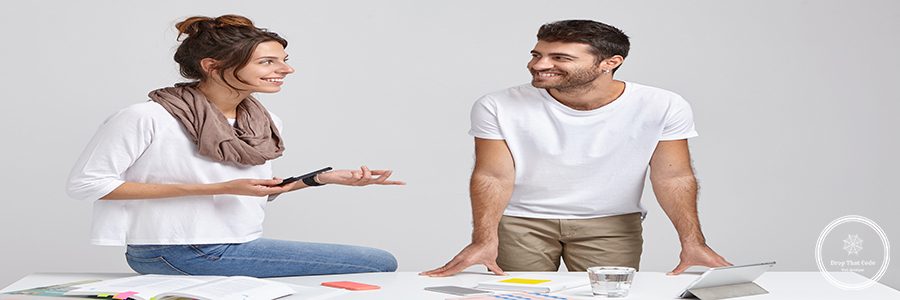 Two man and woman collegaues or partners have active discussion of future plans, look happily at each other. Stylish young female designer sits at desk, explains new strategy to unshaven male worker