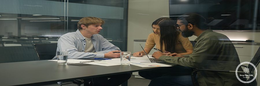 Three diverse business colleagues partners office managers co-workers male female teamwork guys girl woman men planning discuss documents paperwork businessmen businesswoman talk at conference table. High quality 4k footage